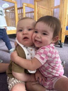 Two babies hugging in the Nursery classroom at Loving Touch Nursery School