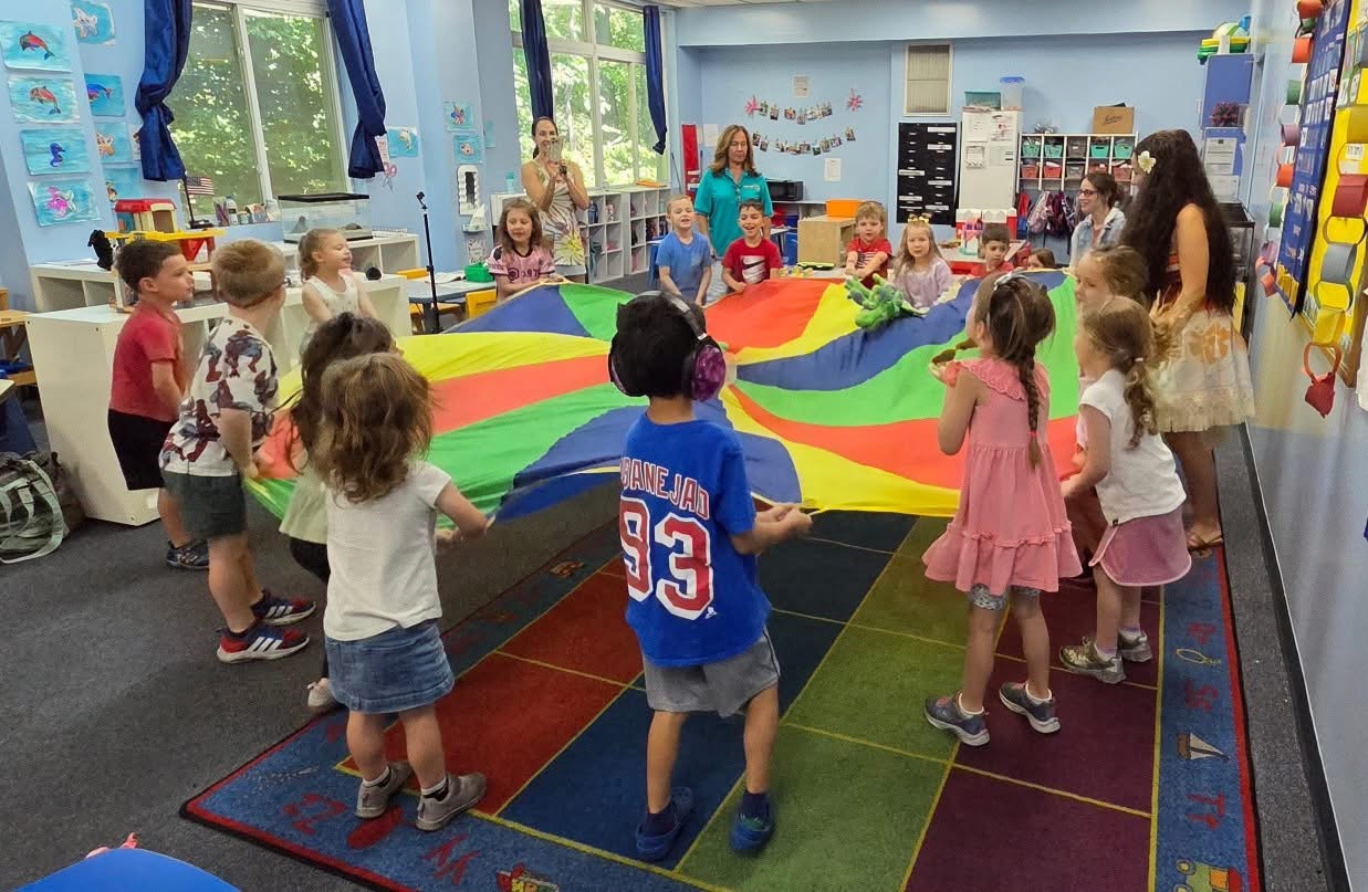 Children enjoying a colorful summer camp parachute activity at Loving Touch Nursery School